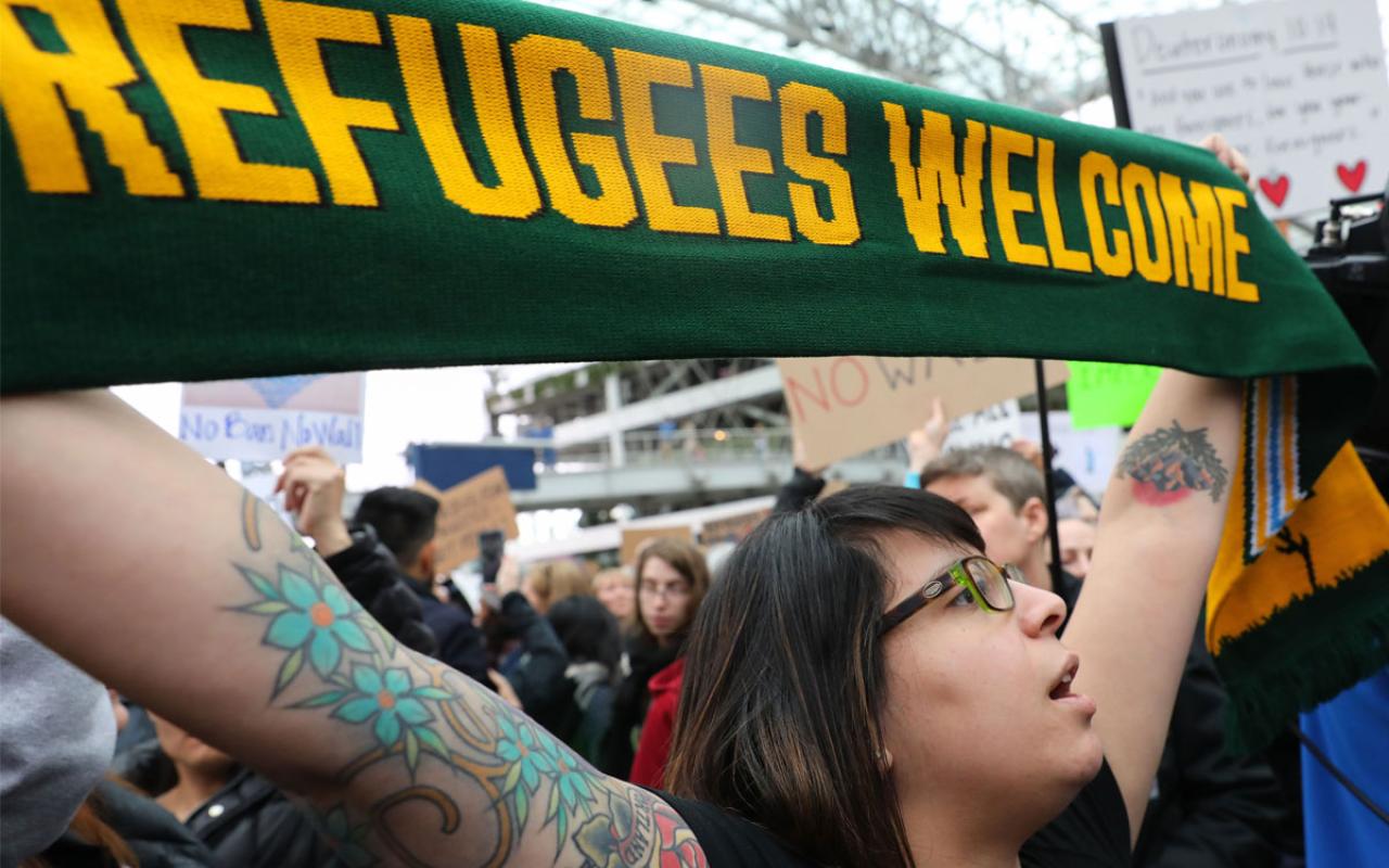 Demonstrators at a January march at Portland International Airport holding a scarf saying "Refugees Welcome" Photo credit: John Rudoff