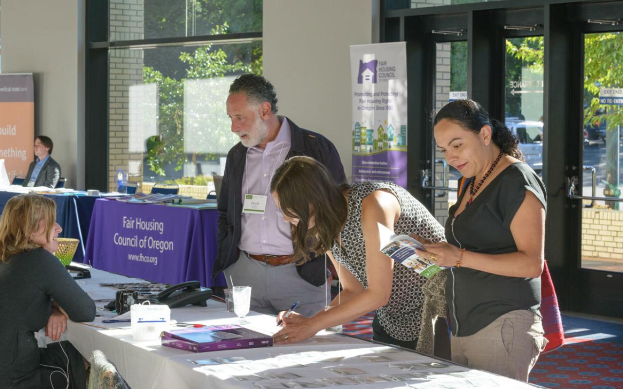 Three people signing up for more information during Oregon Opportunity Network's 2016 Conference. 