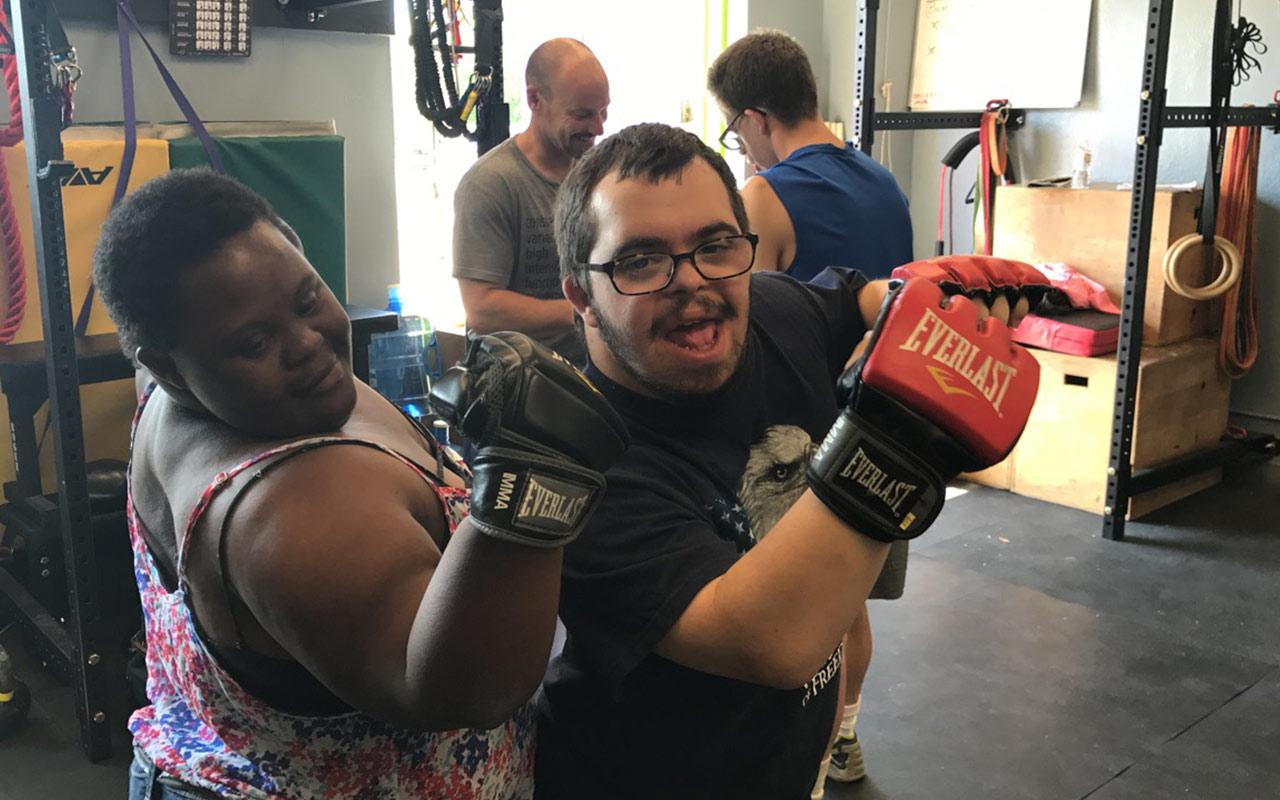 On-The-Move participants, Elizabeth and Spencer, flex their muscles after boxing at a local gym. Photo courtesy of On-The-Move Community Integration