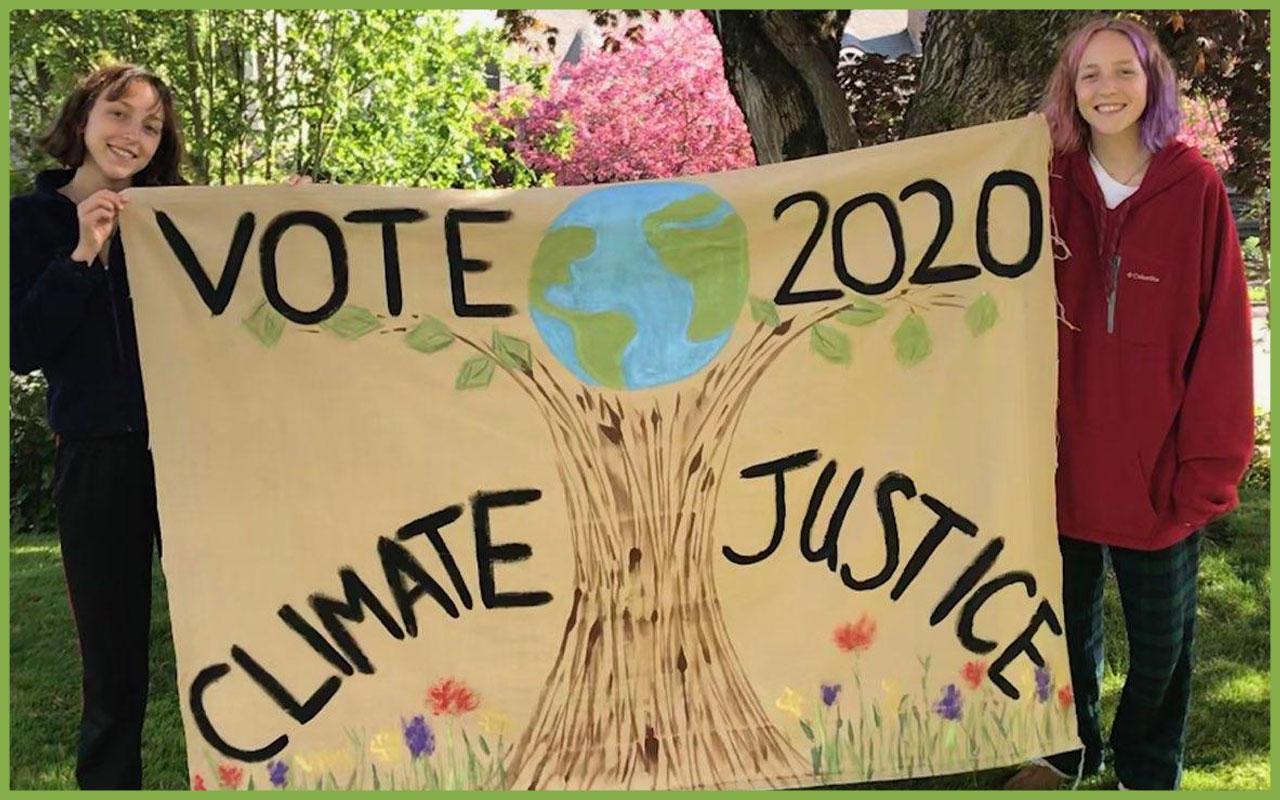 Ella and Devon Burke hold an Earth Day banner they made with their mom, Jill Fuglister.