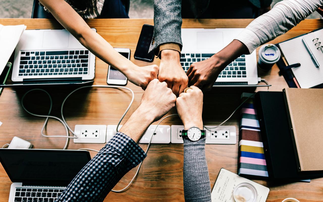 Photo caption: Five people fist bump.