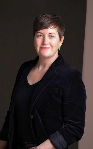 A portrait of Erin in a black blazer