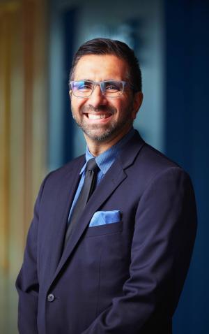 A photo of Michael smiling in a navy suit in the Meyer HQ lobby